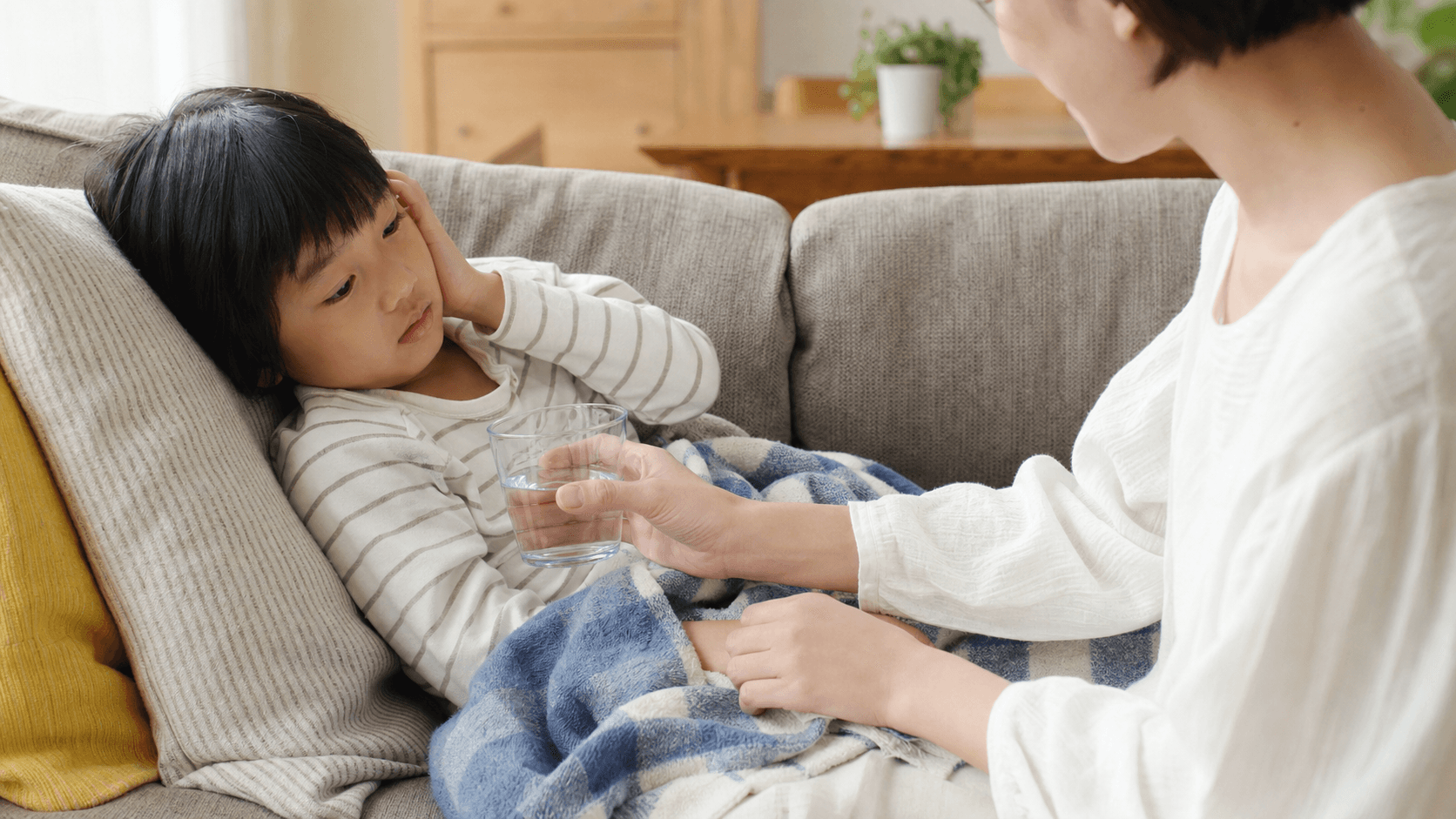 ソファで耳に手を添える子どもに保護者が寄り添っている場面