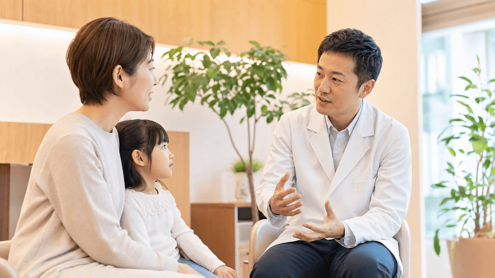 小児科医が保護者と子どもに健康情報について説明している場面