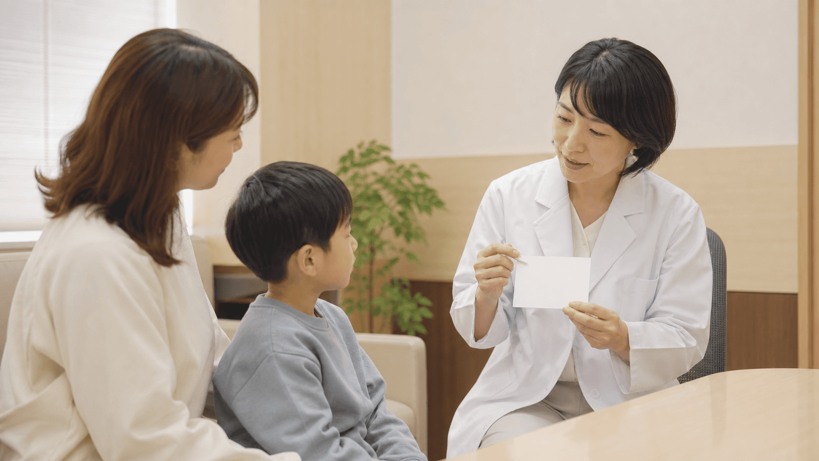 診察室で医師が保護者と子どもに検査について説明している場面