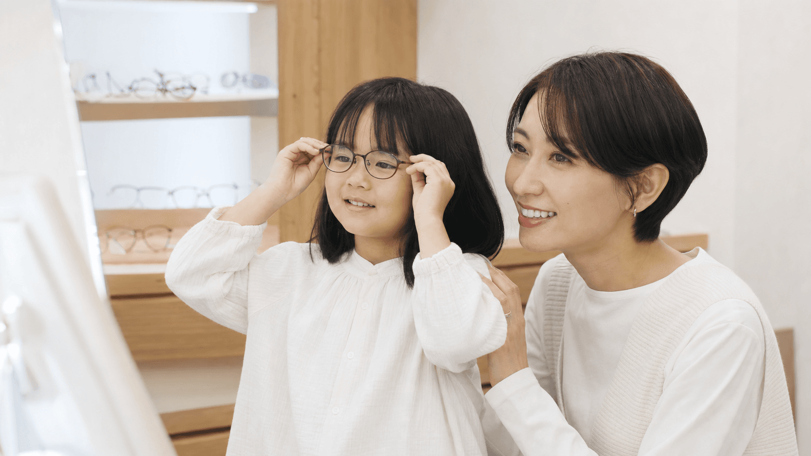 眼鏡店で子どもが眼鏡を試し保護者と鏡を見ている場面