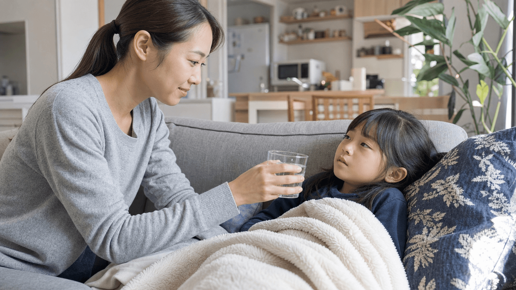 風邪で休む子どもに保護者が水を差し出して様子を見ている場面