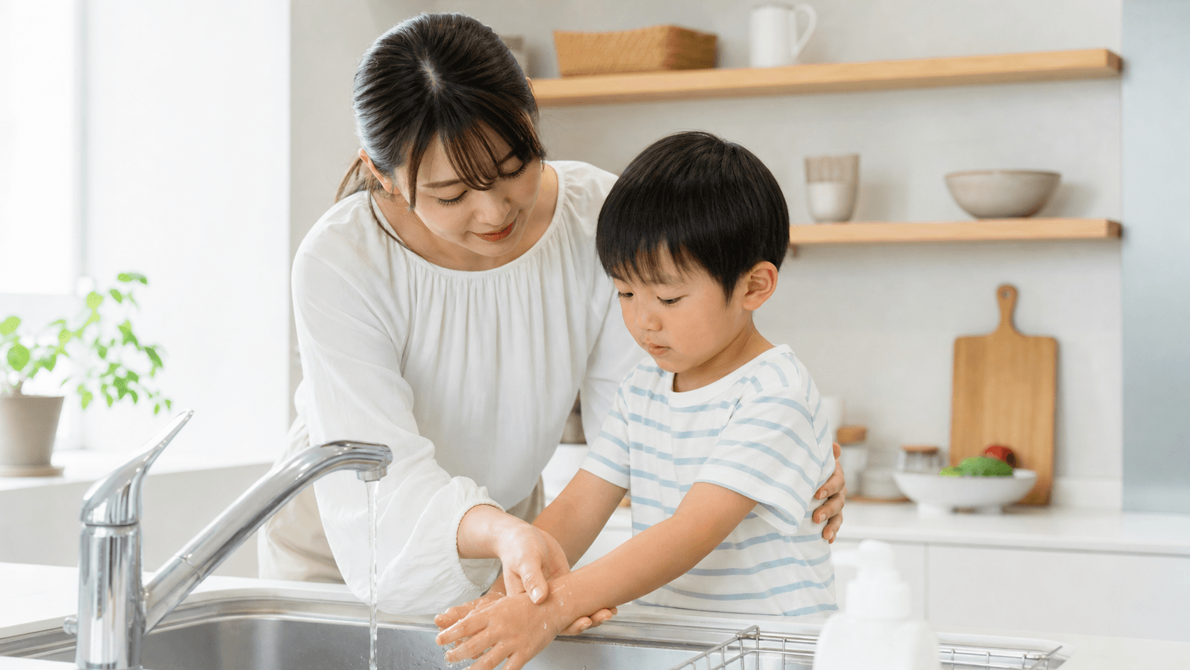キッチンで保護者が子どもの手を流水で冷やしている場面