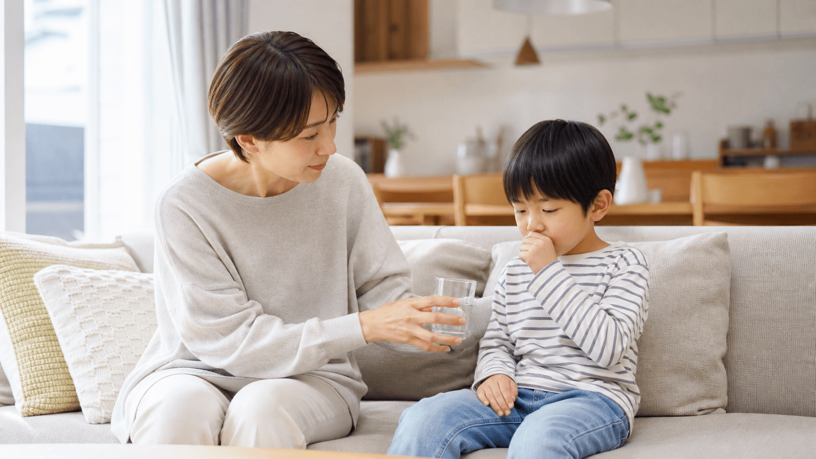 ソファで休む子どもに保護者が水を渡しながら話を聞いている場面