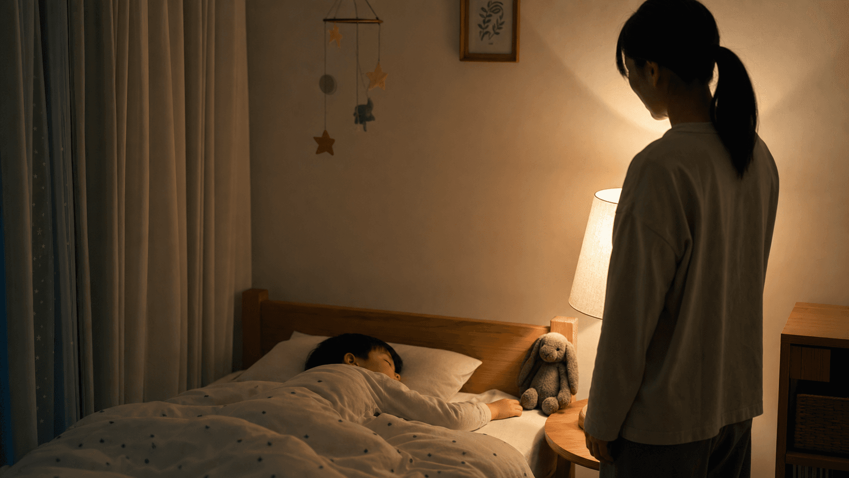 夜中に眠っている子どものそばで保護者が静かに見守っている場面
