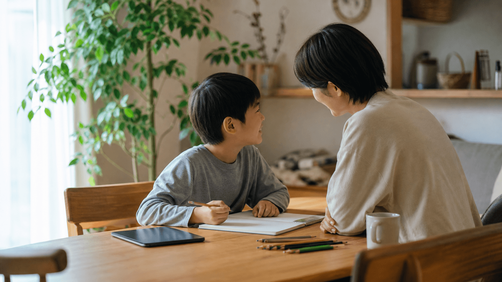 食卓でタブレットを伏せて子どもと保護者が会話している場面